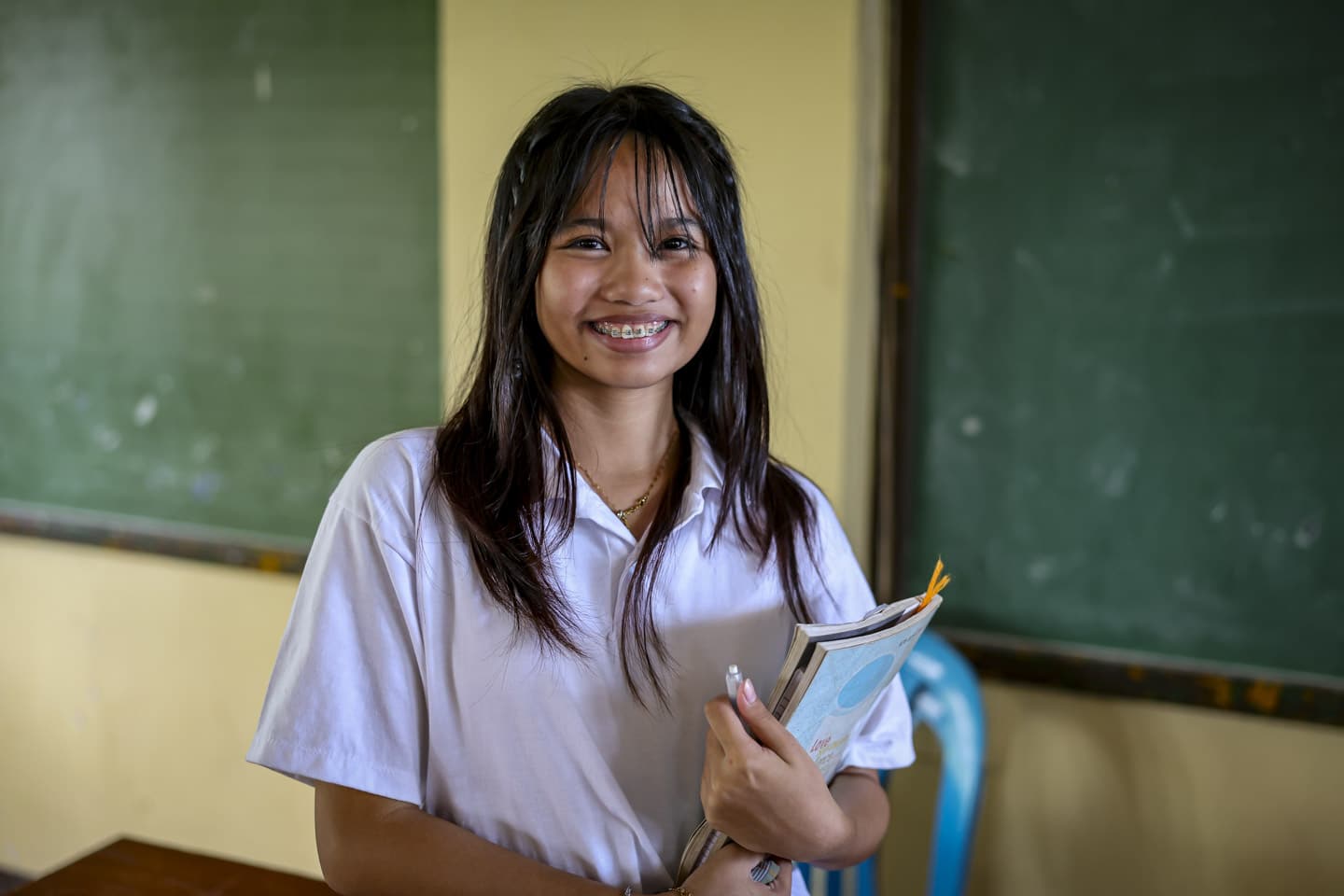 Flicka med skolböcker i klassrum i Filippinerna.