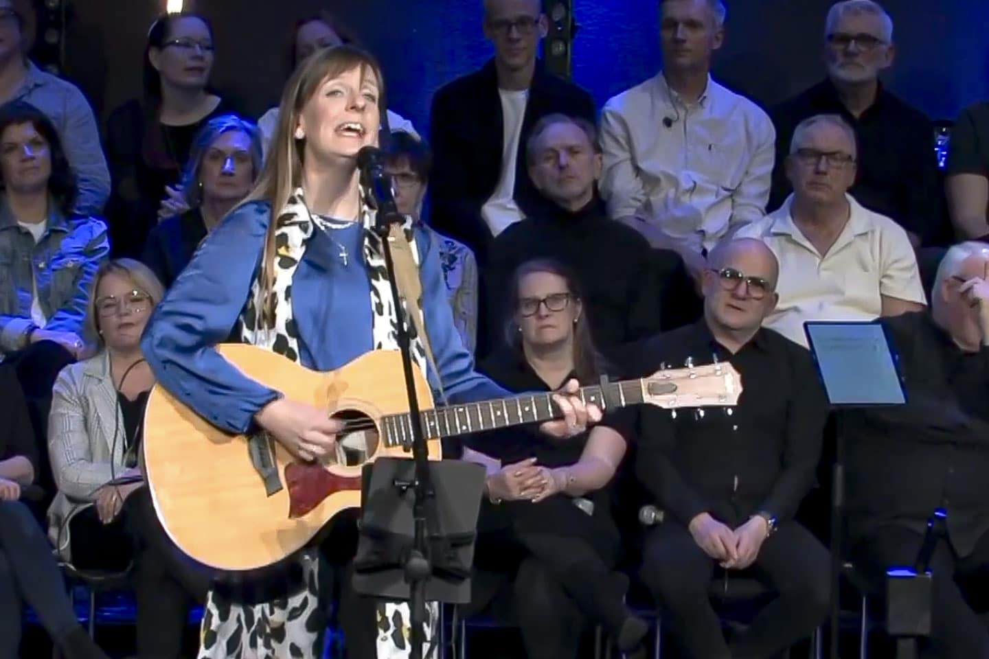 kvinna sjunger och spelar gitarr i kyrka