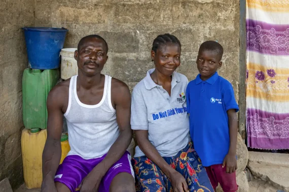 Pojke med mamma och pappa vid familjens hus i Ghana.
